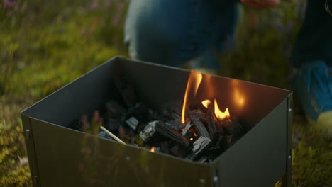 hiker-is-resting-in-camping-preparing-coals-in-chargrill-for-cooking-slow-motion-shot-of-man-and-flames